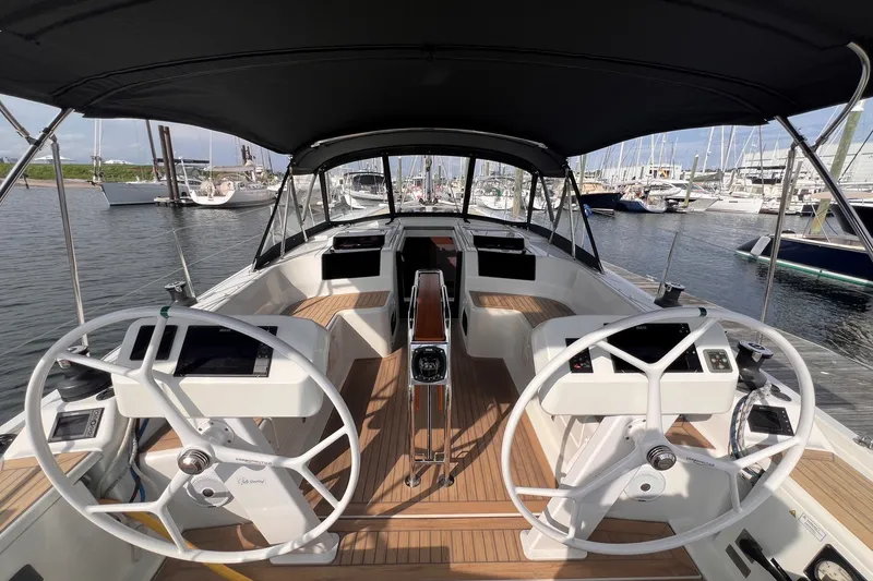 Slide: The Image of 2020 Hanse 458 yacht cockpit with dual steering wheels, docked in a marina. - 23