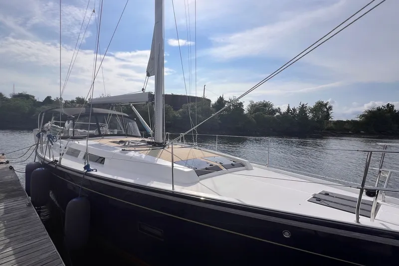 Slide: The Image of 2020 Hanse 458 yacht docked by a serene river under a partly cloudy sky. - 5