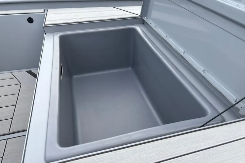Slide: The Image of 2027 Tracker Bass Tracker Classic CC boat storage compartment, open lid, gray interior. - 22