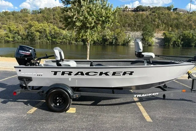 Slide: The Image of 2027 Tracker Super Guide V-16 T boat parked by a scenic riverside. - 55