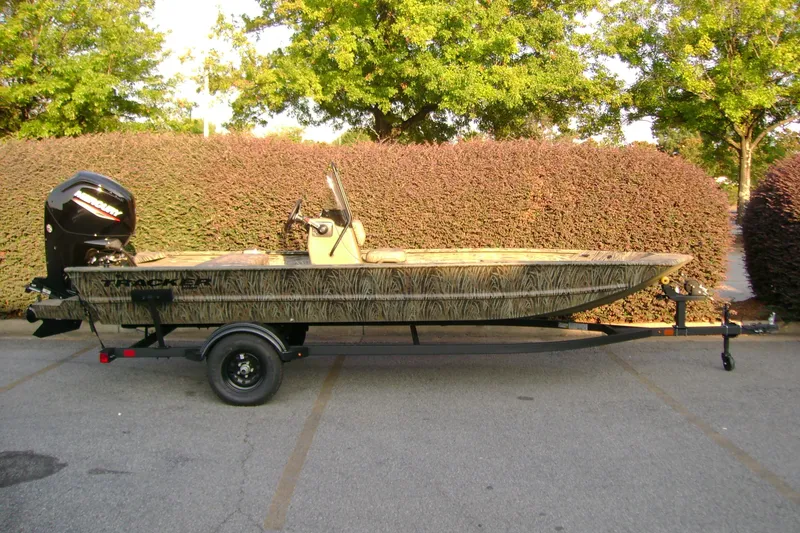 The Image of 2027 Tracker Grizzly 1860 CC boat on trailer, parked outdoors with lush greenery background. - 0