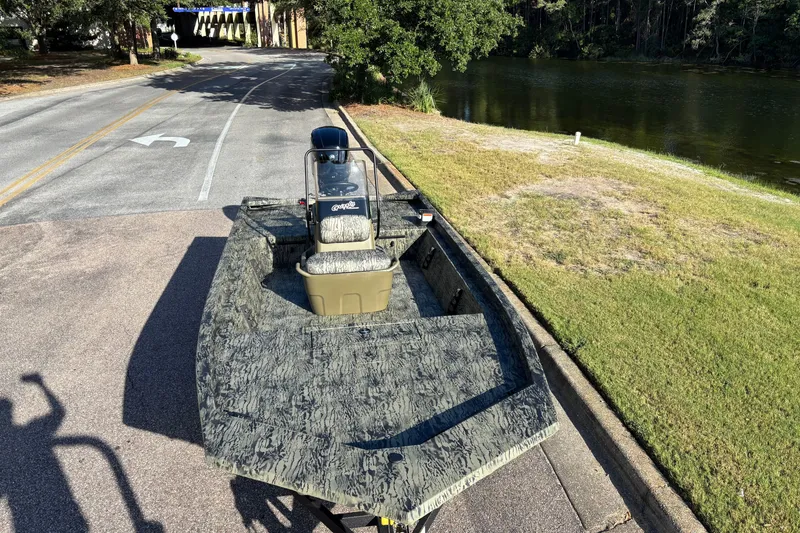 Slide: The Image of 2027 Tracker Grizzly 1860 CC boat on a road near a lake, showcasing camo design. - 66
