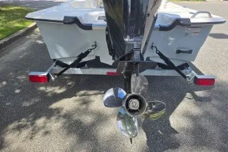 Slide: The Image of 2027 Mako Pro Skiff 17 CC boat trailer with outboard motor, parked on asphalt. - 9