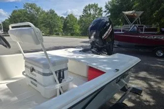 Slide: The Image of 2027 Mako Pro Skiff 17 CC boat with outboard motor in a sunny parking area. - 5