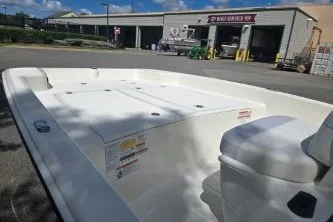 Slide: The Image of 2027 Mako Pro Skiff 17 CC boat at a service center under a clear blue sky. - 6