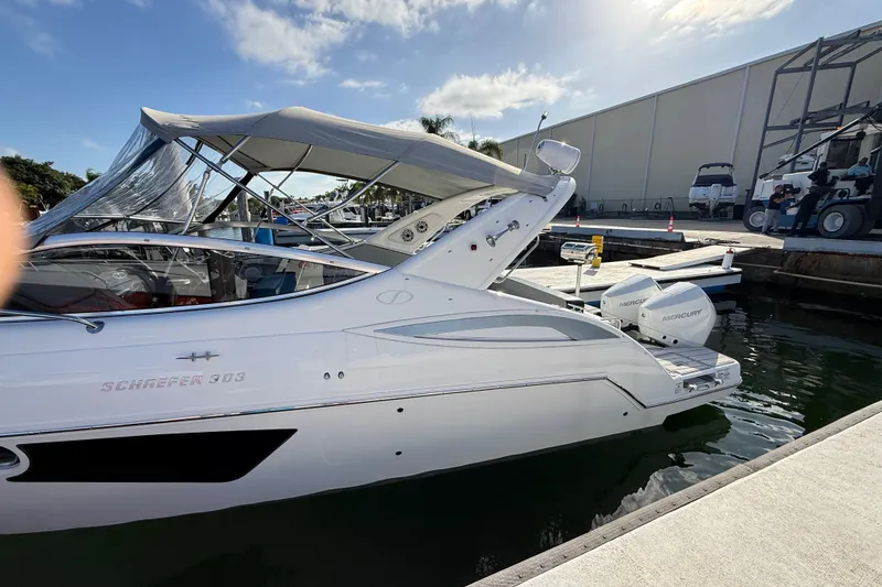 Slide: The Image of 2021 Schaefer 303 boat docked, featuring sleek design and Mercury outboard engines. - 9