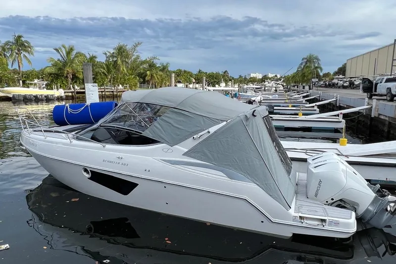 Slide: The Image of Schaefer 303 boat docked, 2021 model, with canopy, in a marina setting. - 2