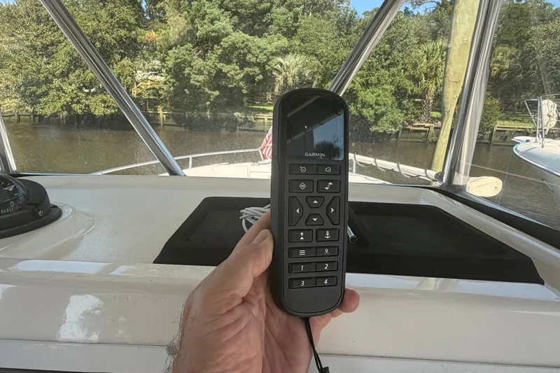 Slide: The Image of Hand holding Garmin remote on 2001 Century 2900 Center Console boat, with scenic waterway view. - 40