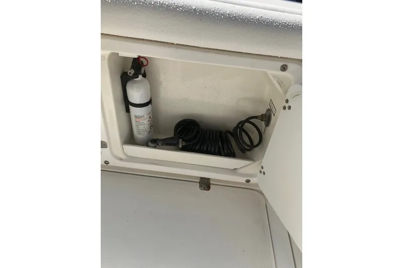 Slide: The Image of Storage compartment on a 2001 Century 2900 Center Console with fire extinguisher and coiled hose. - 54