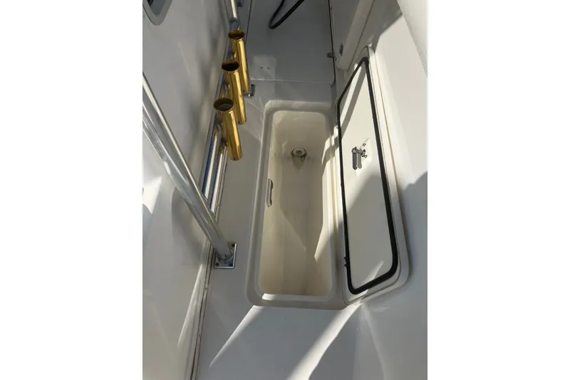 Slide: The Image of 2001 Century 2900 Center Console boat interior with storage compartment and rod holders. - 58