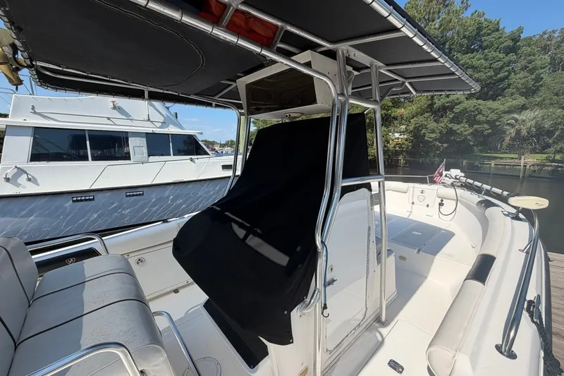 Slide: The Image of 2001 Century 2900 Center Console boat interior with seating and canopy, docked near another vessel. - 4