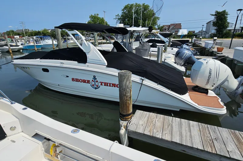 The Image of 2018 Searay 270 SLX boat docked, covered, with "Shore Thing" text on the side. - 1
