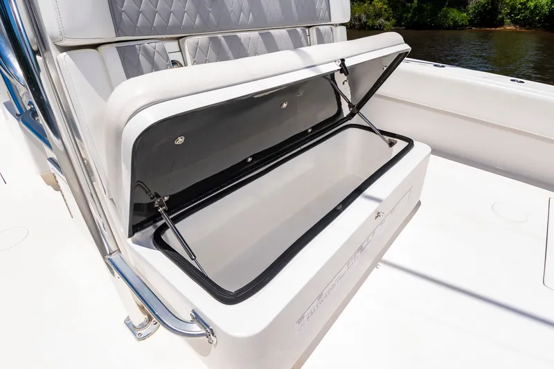 Slide: The Image of An open storage compartment on a white boat with cushioned seats in the background. - 23