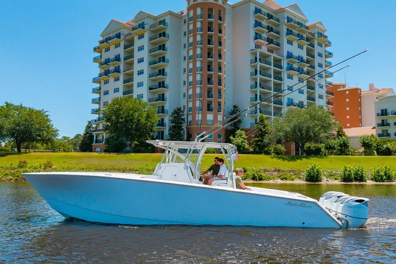 The Image of A 2022 SeaHunter 38 CTS cruising on a river in front of a large residential building. - 0
