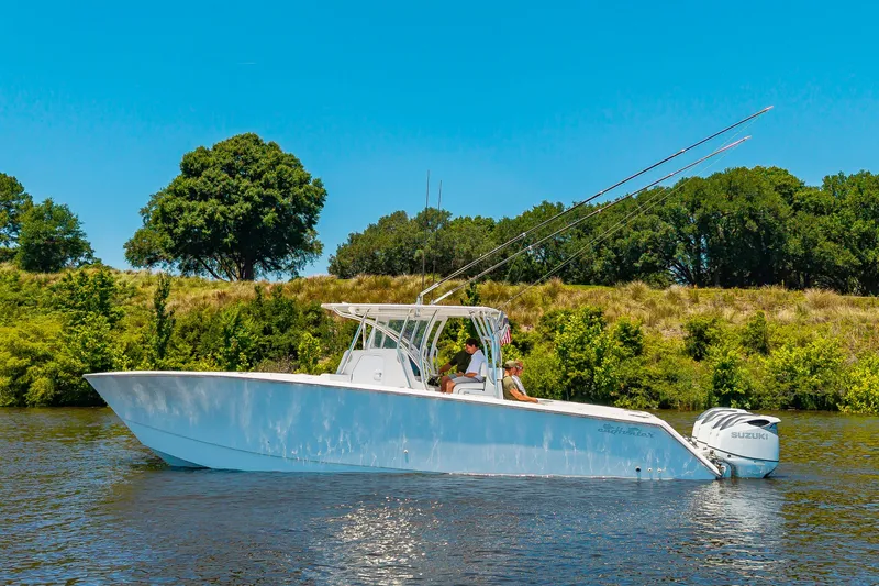 Slide: The Image of A 2022 SeaHunter 38 CTS on calm water, surrounded by green trees. - 39