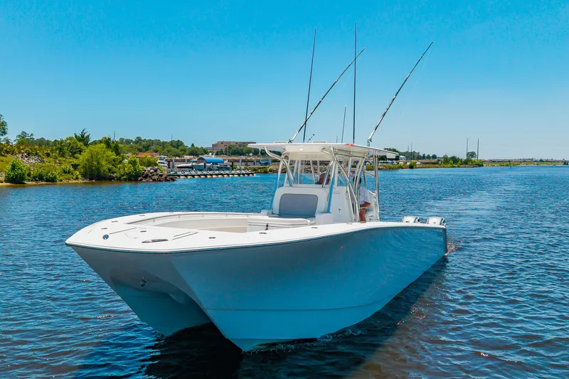 Slide: The Image of A 2022 SeaHunter 38 CTS on calm water with two fishing rods and a clear sky. - 48