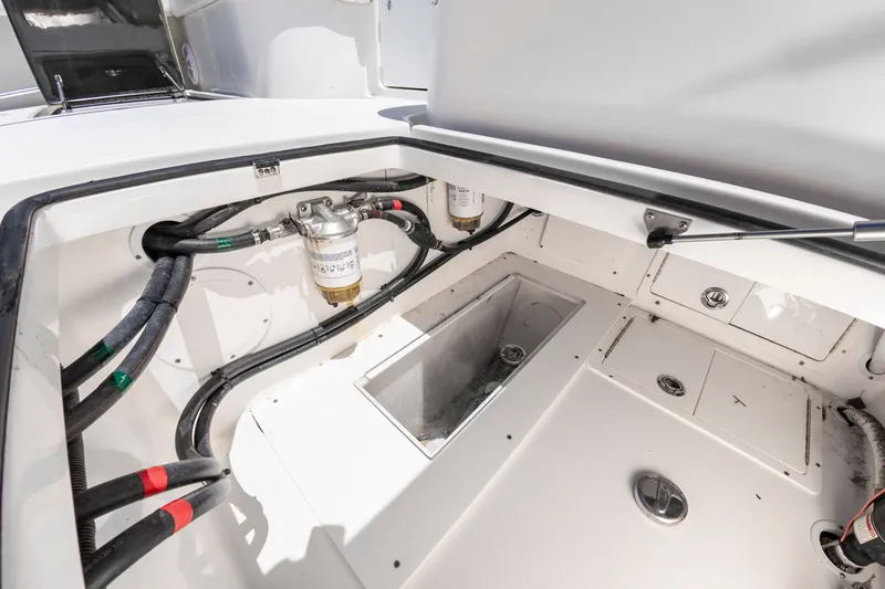 Slide: The Image of An open storage compartment on a SeaHunter 38 CTS boat, showing hoses and filters. - 25