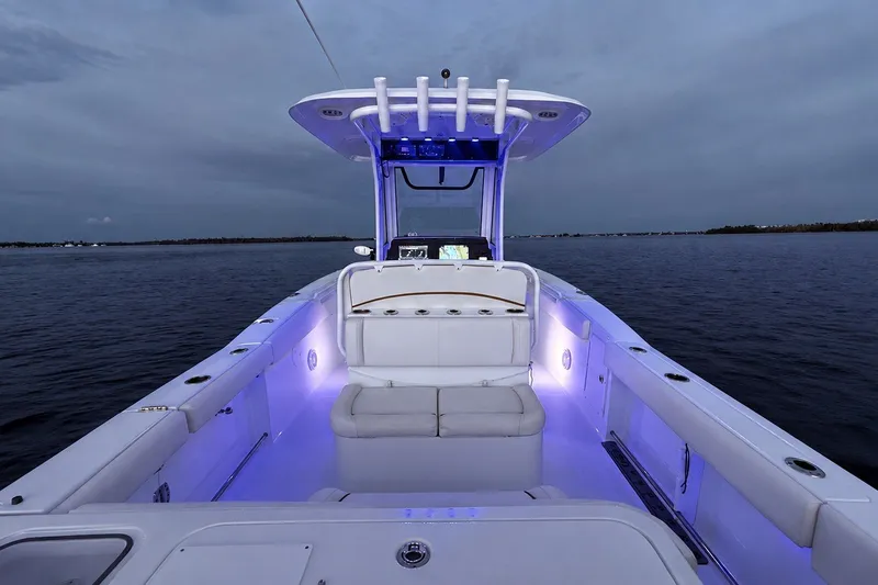 Slide: The Image of 2022 Sea Hunt Gamefish 27FS boat with illuminated deck, on calm waters at dusk. - 41