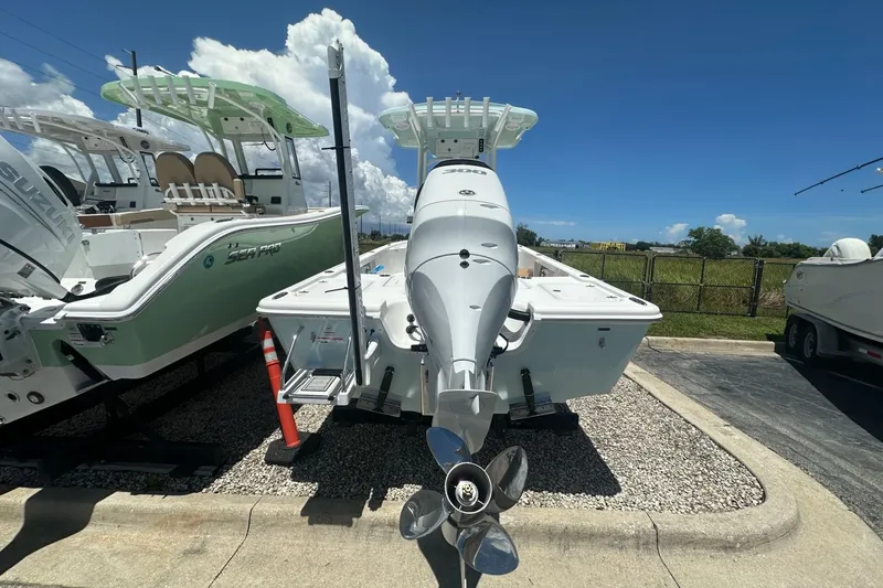 Slide: The Image of 2026 Sea Pro 250 Bay boat with outboard motor, parked outdoors under clear sky. - 2