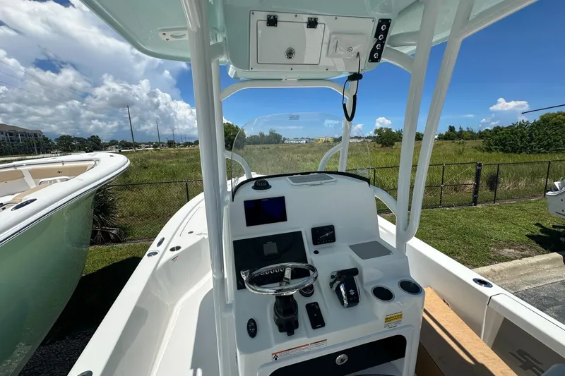Slide: The Image of 2026 Sea Pro 250 Bay boat console with steering wheel and controls, parked outdoors. - 3