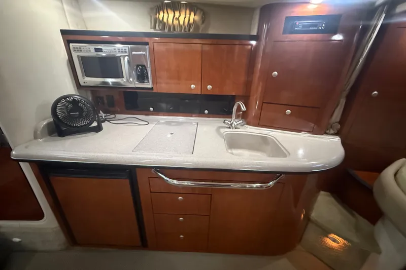 Slide: The Image of 2007 Sea Ray 340 Sundancer galley with microwave, sink, and wooden cabinetry. - 18