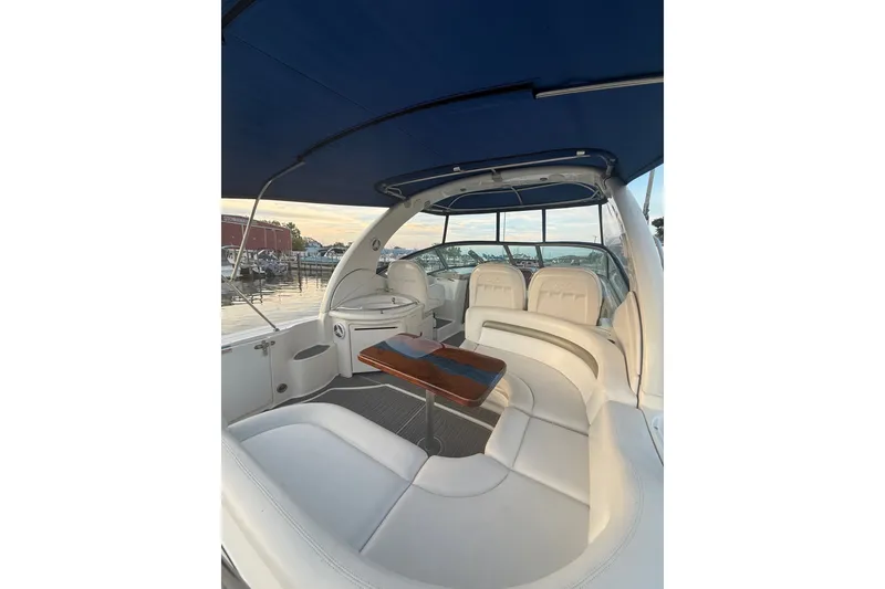 Slide: The Image of 2007 Sea Ray 340 Sundancer interior with white seating and wooden table, docked at marina. - 9