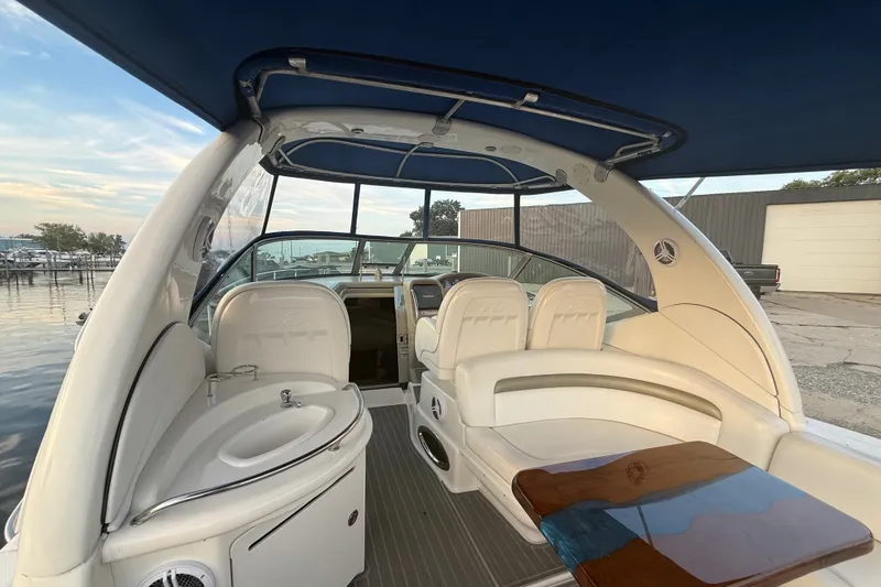 Slide: The Image of 2007 Sea Ray 340 Sundancer interior with seating, sink, and wooden table under blue canopy. - 8