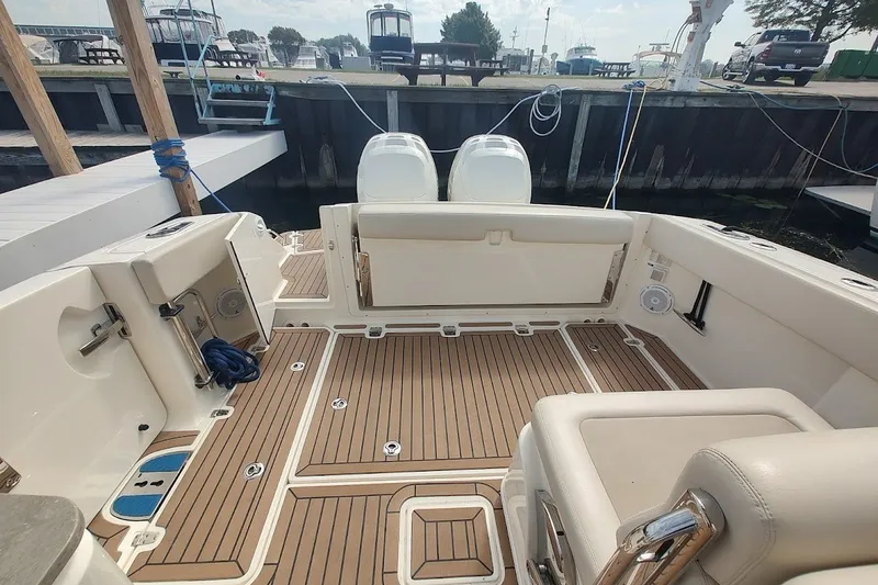 Slide: The Image of 2018 Boston Whaler 320 Vantage boat interior with teak flooring at a marina. - 58