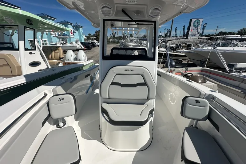 Slide: The Image of 2026 Sea Pro 262 Offshore boat interior with seating and helm, displayed at a marina. - 5