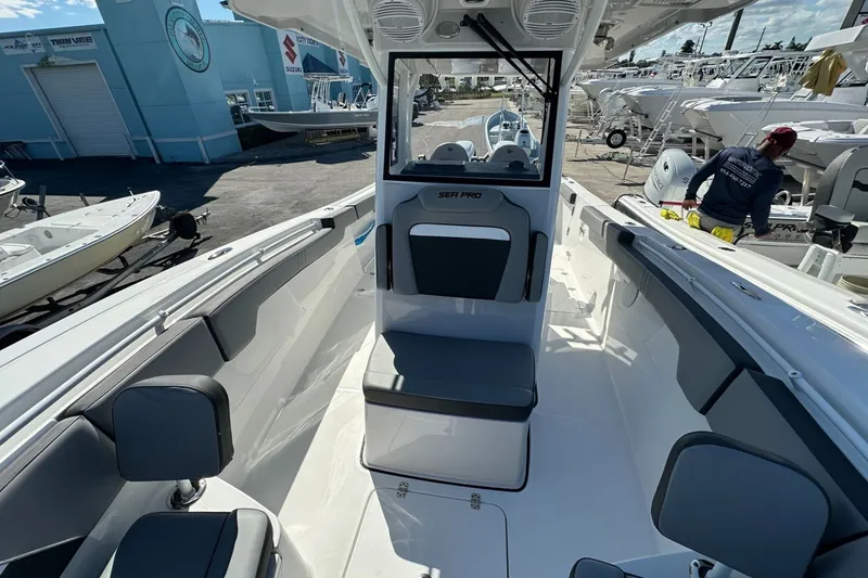 Slide: The Image of 2026 Sea Pro 292 DLX boat interior with seating and helm, displayed at a marina. - 7