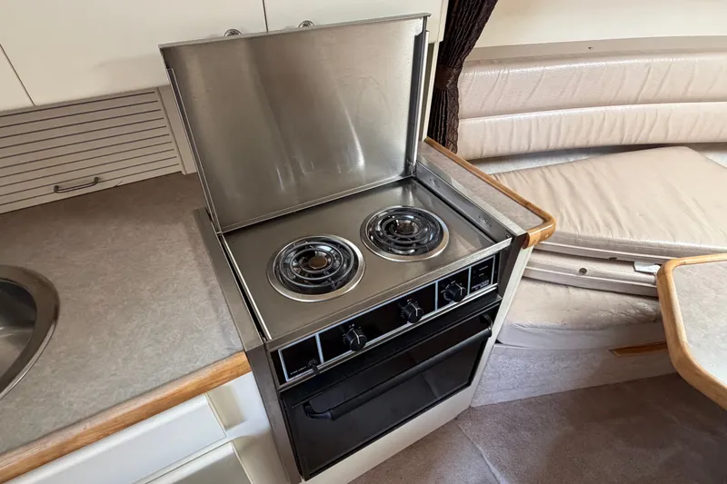 Slide: The Image of 1996 Carver 325 Aft Cabin Motor Yacht kitchen with stove and seating area. - 18