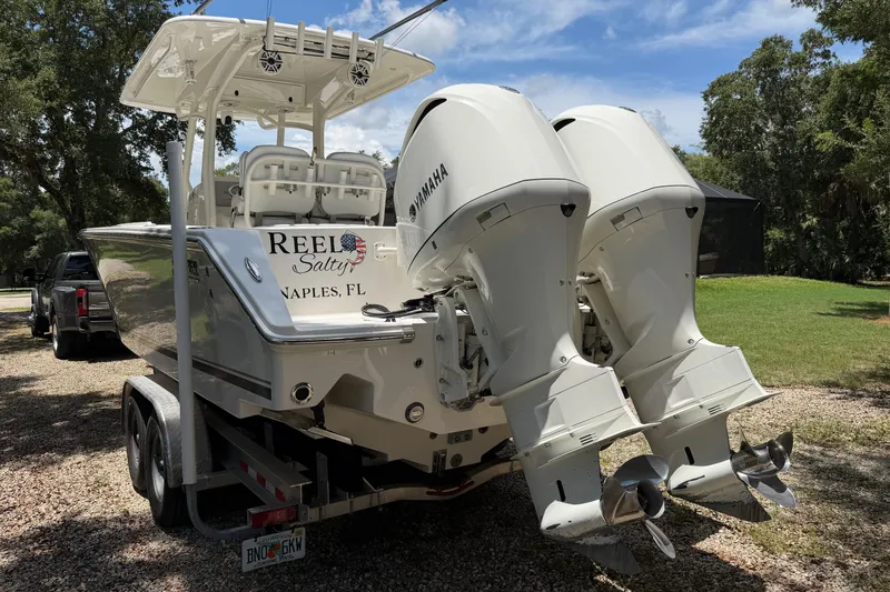 Slide: The Image of 2019 Jupiter 30 boat with dual Yamaha engines on a trailer in a sunny yard. - 7