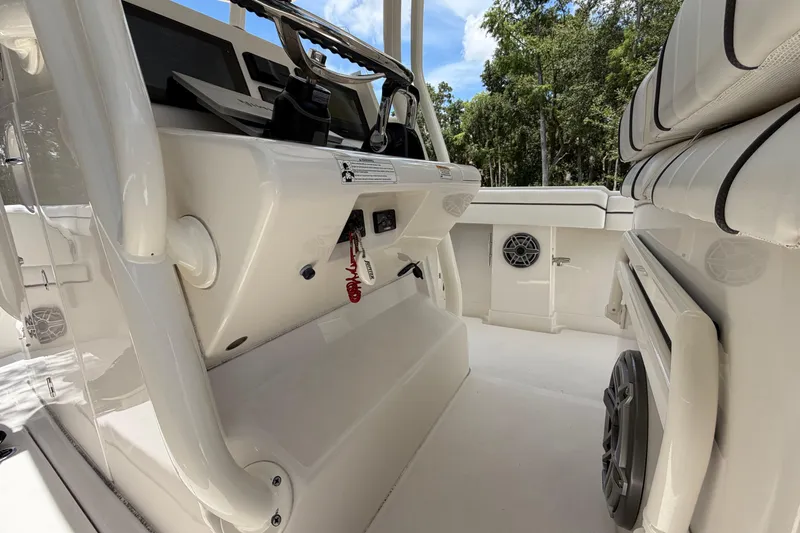 Slide: The Image of 2019 Jupiter 30 boat interior with modern dashboard and seating, surrounded by lush greenery. - 17