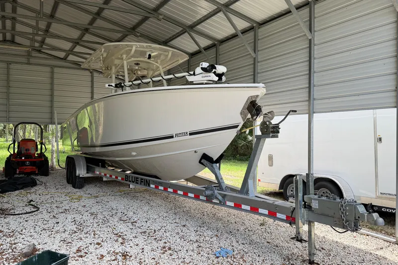 Slide: The Image of 2019 Jupiter 30 boat on trailer under metal shelter, with tractor nearby. - 11