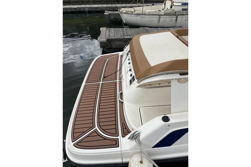 Slide: The Image of 2021 Bayliner VR6 Bowrider I/O docked, featuring a sleek swim platform and cushioned seating. - 1
