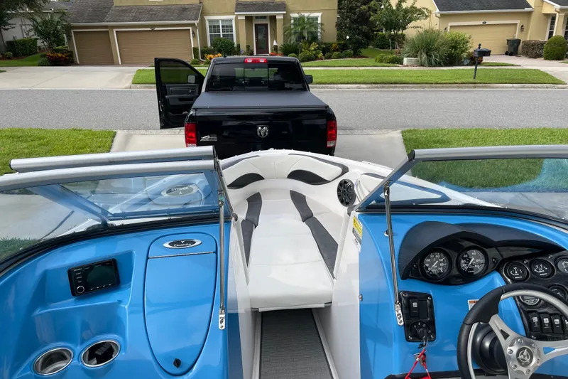 Slide: The Image of 2021 Campion Allante 180 boat interior with blue dashboard, parked in a residential driveway. - 4