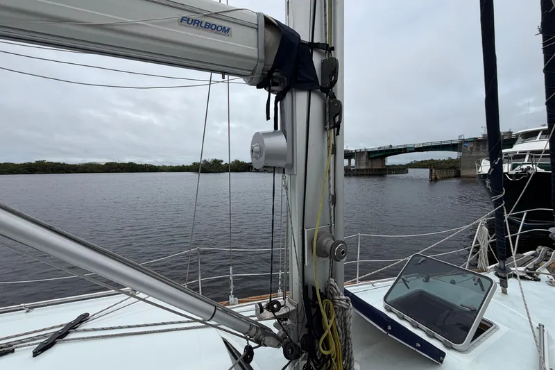 Slide: The Image of Sailboat deck view with mast and boom, near a bridge on a cloudy day. - 16