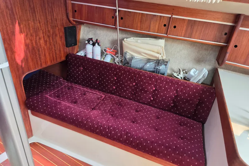 Slide: The Image of Interior of 1989 Ericson Olsen 34 sailboat with maroon cushioned seating and wooden cabinetry. - 5