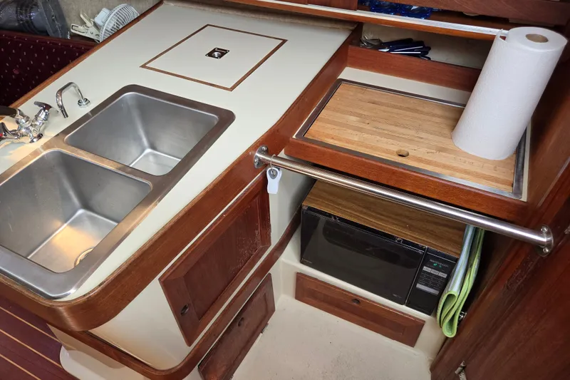 Slide: The Image of 1989 Ericson Olsen 34 yacht kitchen with double sink, cutting board, and microwave. - 11