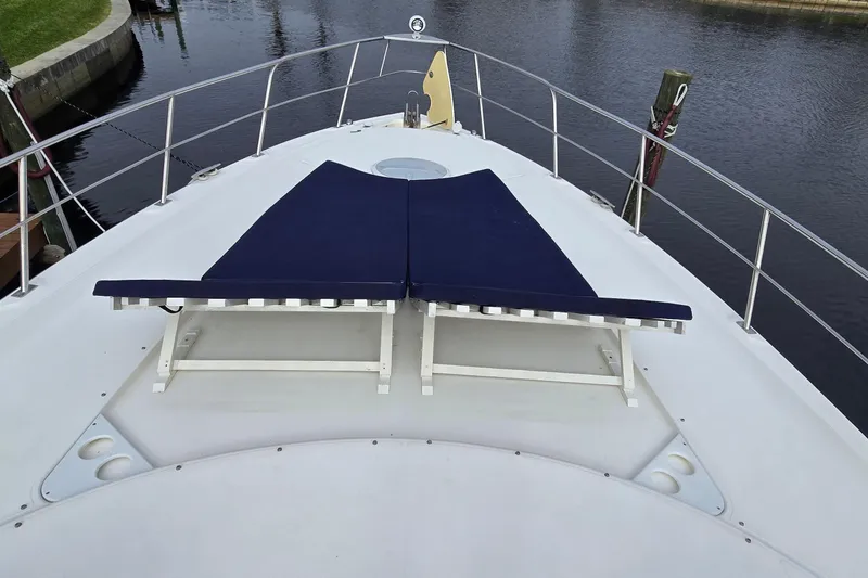 Slide: The Image of 2006 Cruisers Yachts 520 Express deck with blue sun loungers, docked by calm water. - 35