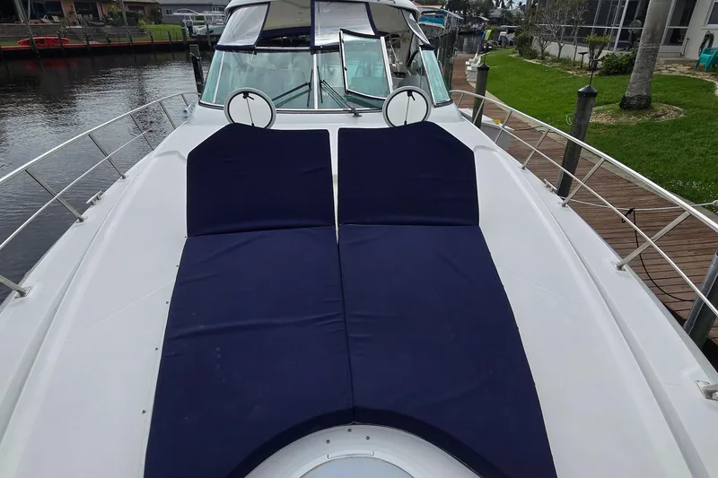 Slide: The Image of 2006 Cruisers Yachts 520 Express with blue sun pads on deck, docked by waterfront. - 34