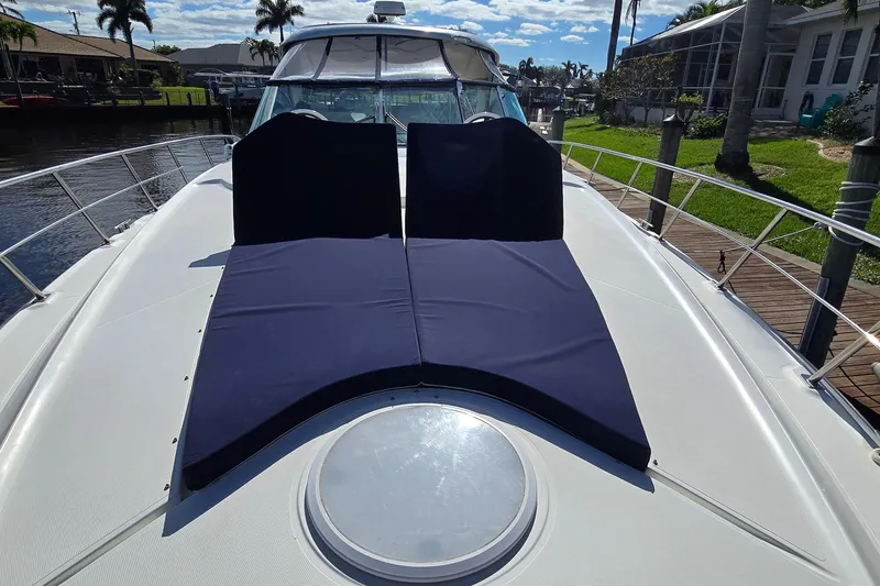 Slide: The Image of 2006 Cruisers Yachts 520 Express with sun pads on deck, docked by waterfront homes. - 32