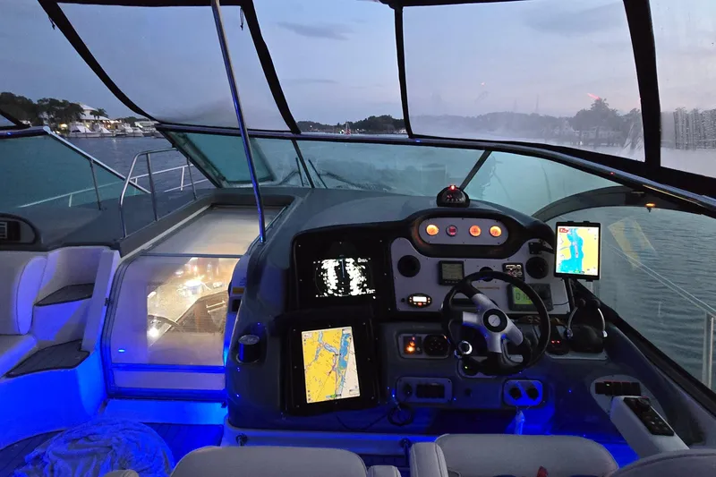 Slide: The Image of 2006 Cruisers Yachts 520 Express cockpit with illuminated controls and navigation screens at dusk. - 20