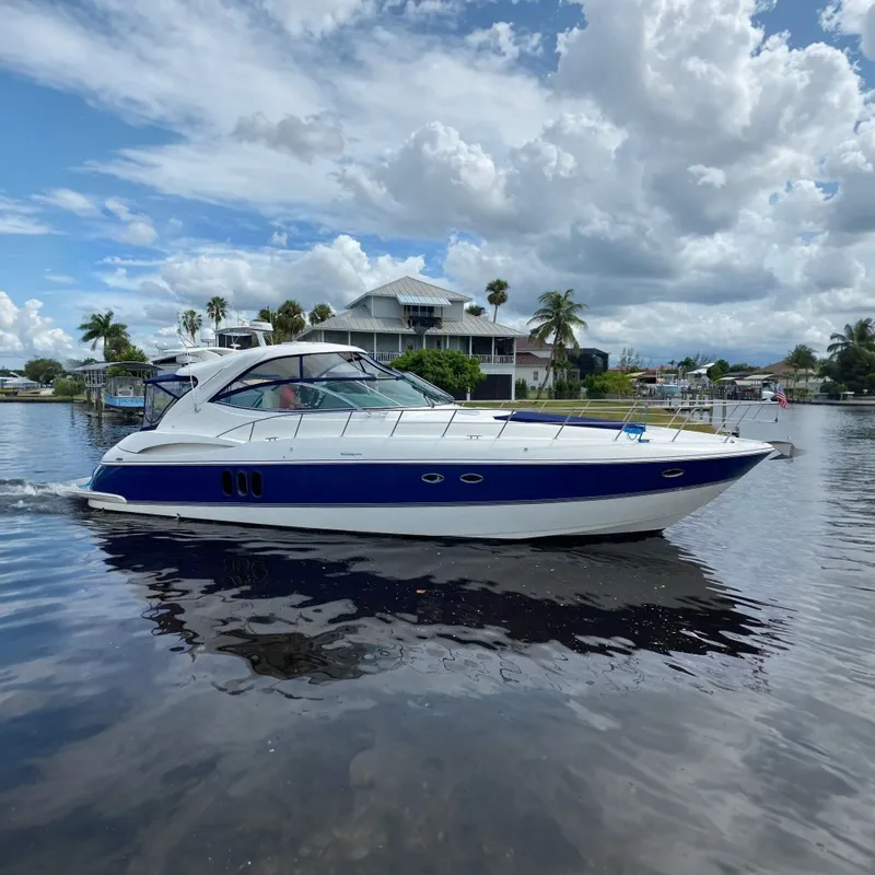 The Image of 2006 Cruisers Yachts 520 Express on calm water, with a scenic waterfront backdrop. - 0