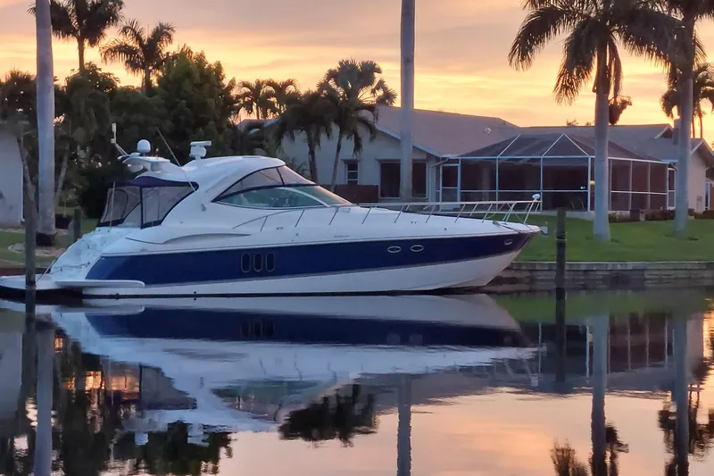 Slide: The Image of 2006 Cruisers Yachts 520 Express docked at sunset, surrounded by palm trees. - 5