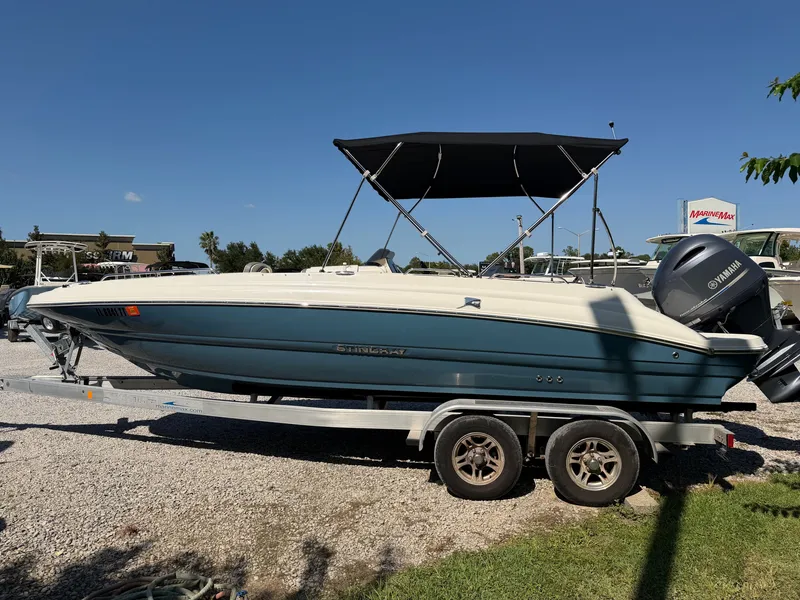 Slide: The Image of A 2024 Stingray 212 SC boat on a trailer with a black sunshade and Yamaha engine. - 2