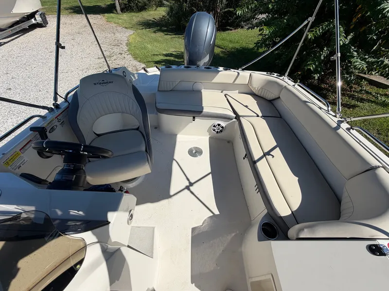 Slide: The Image of The image shows the cockpit of a 2024 Stingray 212 SC boat with beige seating and a helm. - 6