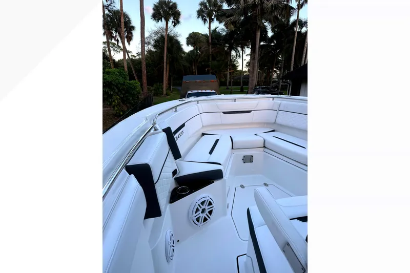 Slide: The Image of 2021 Blackfin 272 CC boat interior with white seating and palm trees in the background. - 9