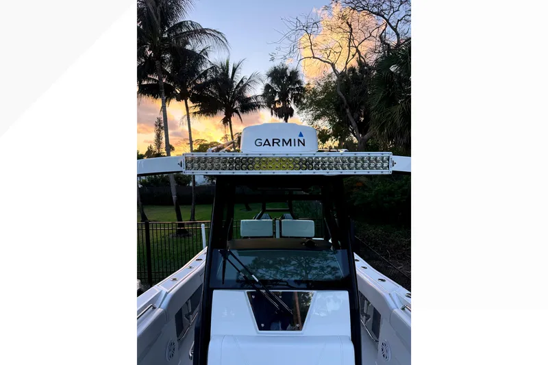 Slide: The Image of 2021 Blackfin 272 CC boat with Garmin equipment at sunset, surrounded by palm trees. - 13