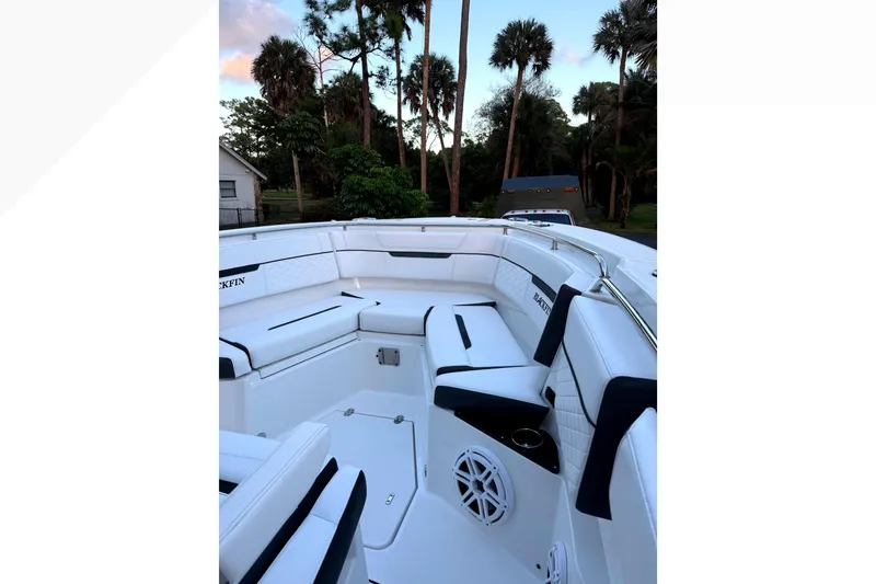 Slide: The Image of 2021 Blackfin 272 CC boat interior with white seating and speaker, surrounded by palm trees. - 10